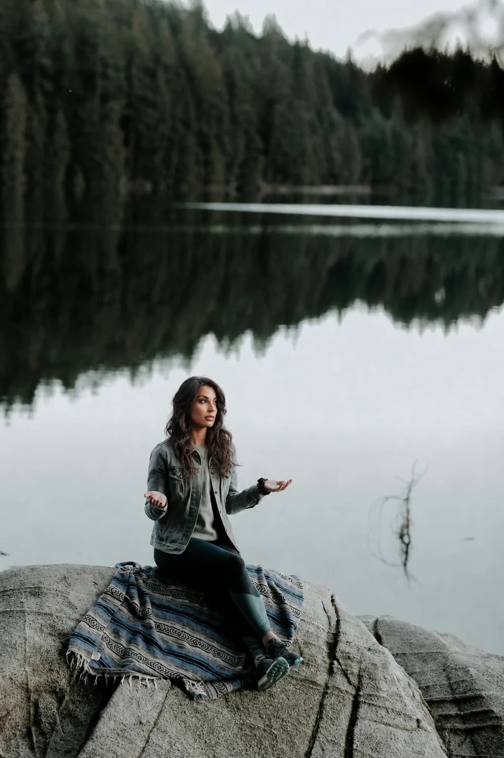 Femme en méditation sur un rocher au bord d'un lac calme